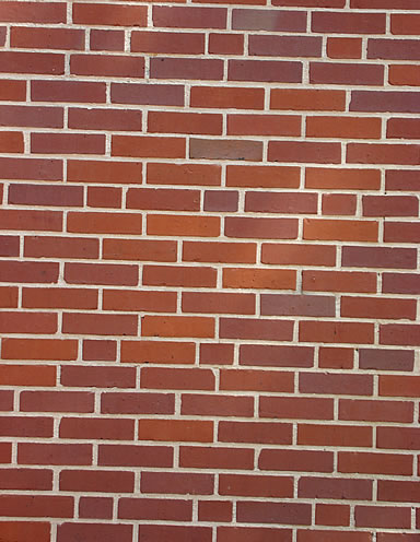 Red brick wall with staggered joints and light-colored mortar.